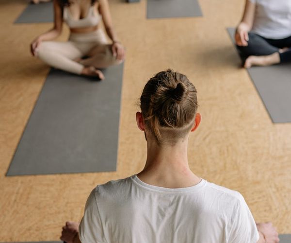 A group of smiling seniors sitting on yoga mats in a bright studio.