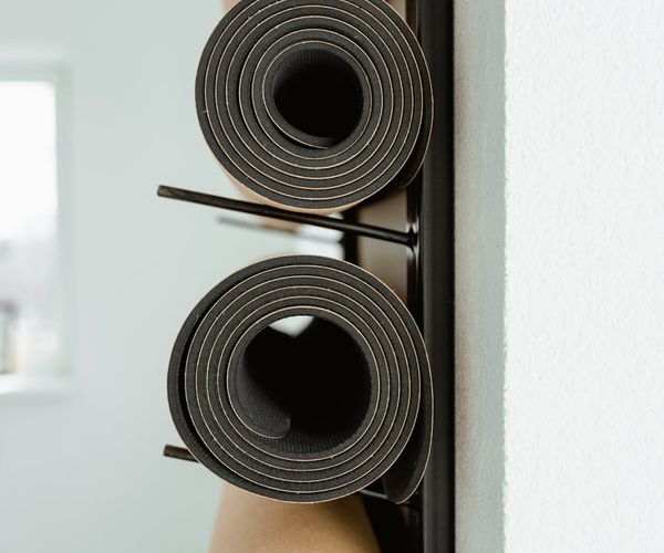 Neatly rolled yoga mats and props ready for a class in a studio.