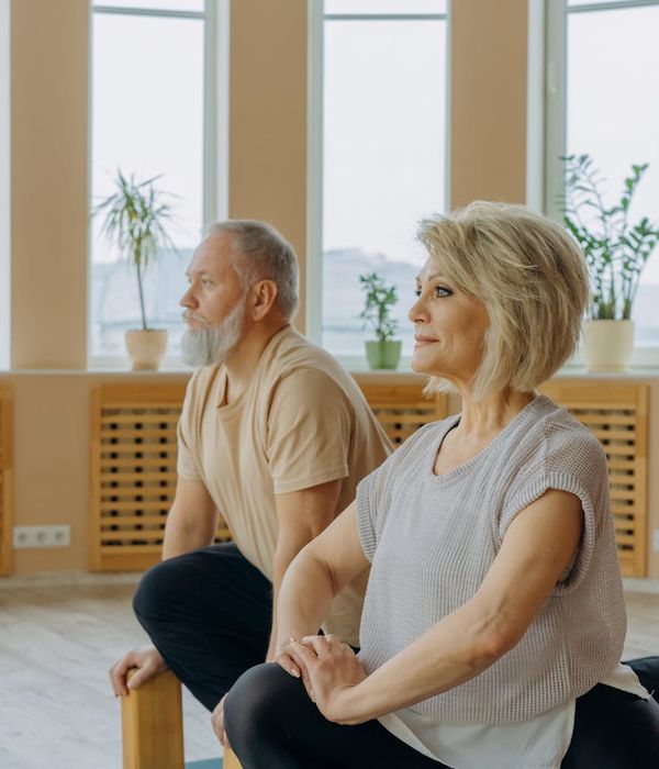 Senior woman practicing a gentle yoga pose in a calm, well-lit room.